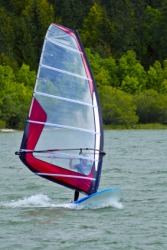 A person boardsailing or windsurfing. A person boardsailing or windsurfing.
