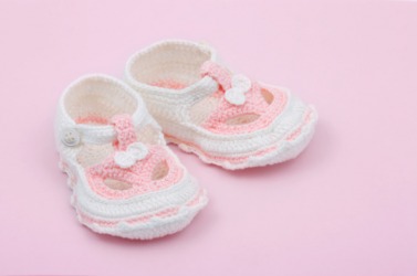 A pair of pink and white baby bootees. A pair of pink and white baby bootees.