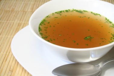 This bowl of bouillon has been garnished with parsley. This bowl of bouillon has been garnished with parsley.