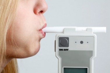 A woman using a breathalyzer. A woman using a breathalyzer.