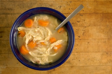 A bowl of noodles and carrots in broth. A bowl of noodles and carrots in broth.