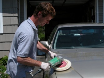 A man using a buffing wheel to polish his automobile. A man using a buffing wheel to polish his automobile.