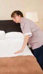 A hotel chambermaid making a bed. A hotel chambermaid making a bed.