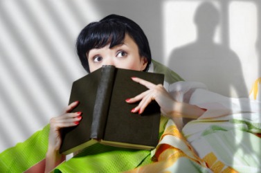 The chiller the woman is reading is causing her to imagine things. The chiller the woman is reading is causing her to imagine things.