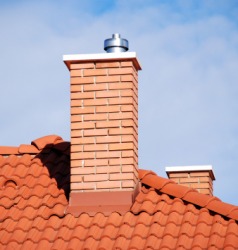A brick chimney on a tiled roof. A brick chimney on a tiled roof.