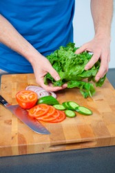 A man cutting vegetables on a chopping block. A man cutting vegetables on a chopping block.