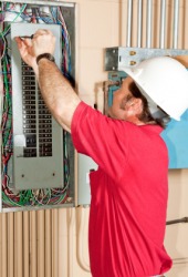An electrician installing a circuit breaker. An electrician installing a circuit breaker.