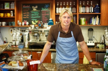 A man standing behind the counter at a coffee shop. A man standing behind the counter at a coffee shop.