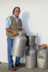 A dairyman holding milk canisters. A dairyman holding milk canisters.