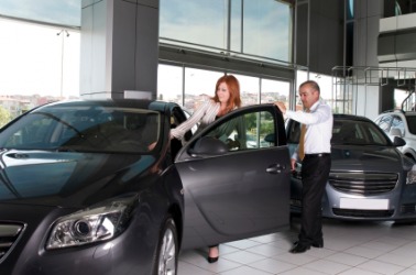 A woman inspecting a new car at an automobile dealership. A woman inspecting a new car at an automobile dealership.