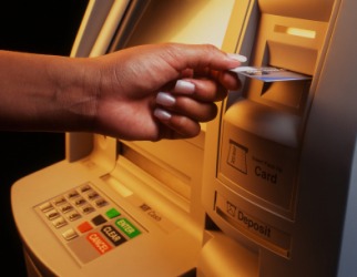 A woman using a debit card at an ATM. A woman using a debit card at an ATM.