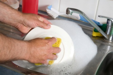 A man washing a dish in dishwater. A man washing a dish in dishwater.