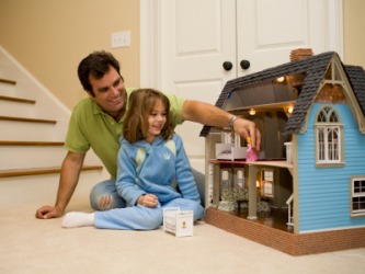 A little girl and her father playing with a dollhouse. A little girl and her father playing with a dollhouse.