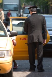 A doorman opening the door of a taxi. A doorman opening the door of a taxi.
