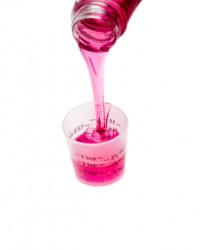 Medicine being poured into a measuring cup to ensure the right dosage. Medicine being poured into a measuring cup to ensure the right dosage.
