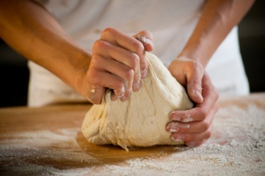 A baker kneads a lump of dough. A baker kneads a lump of dough.