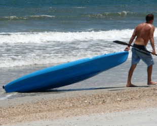 A man dragging his kayak behind him. A man dragging his kayak behind him.