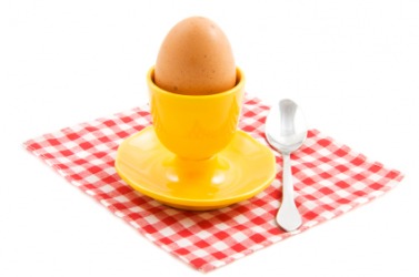 A hard boiled egg in a bright yellow eggcup. A hard boiled egg in a bright yellow eggcup.