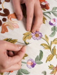 A woman working on a piece of embroidery. A woman working on a piece of embroidery.
