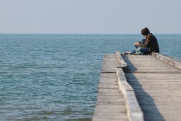 People sitting on the endpoint of a pier. People sitting on the endpoint of a pier.