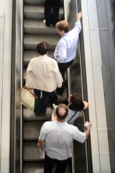 A group of people riding an escalator. A group of people riding an escalator.