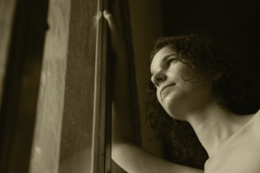 A woman looks out a window with some expectancy. A woman looks out a window with some expectancy.