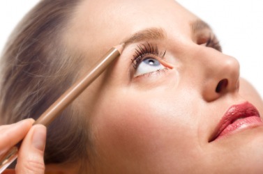 A woman using an eyebrow pencil. A woman using an eyebrow pencil.