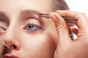 A woman plucking her eyebrow. A woman plucking her eyebrow.