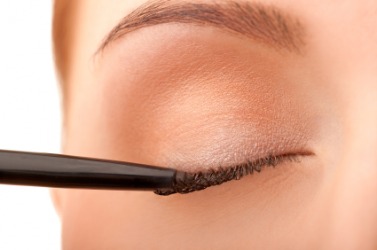 A woman applying eyeliner. A woman applying eyeliner.