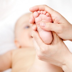 A mother massages her baby's foot. A mother massages her baby's foot.
