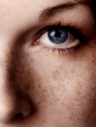 A woman with freckles on her cheek. A woman with freckles on her cheek.