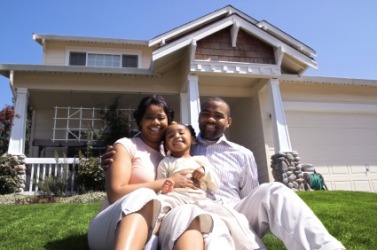 A family sits in front of their home. A family sits in front of their home.