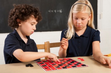 Two children play a game of checkers. Two children play a game of checkers.