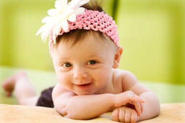 A large flower decorates this babys headband. A large flower decorates this babys headband.