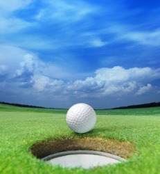 A golf ball about to fall into a hole. A golf ball about to fall into a hole.