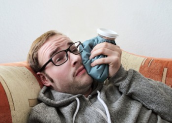 A man applies an ice bag to his face. A man applies an ice bag to his face.