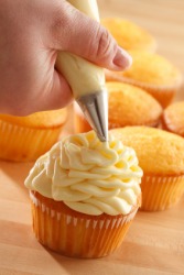 A baker puts icing on a cupcake. A baker puts icing on a cupcake.