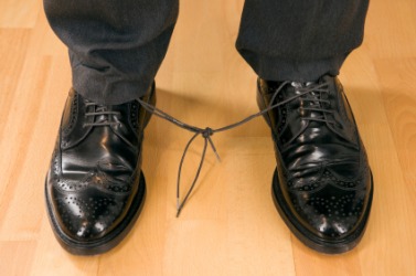 This mans ability to walk is impeded by his shoelaces. This mans ability to walk is impeded by his shoelaces.
