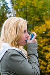 A woman using an inhaler. A woman using an inhaler.