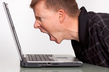 A man gets irate at his computer. A man gets irate at his computer.