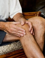 A man massaging his knee joint. A man massaging his knee joint.