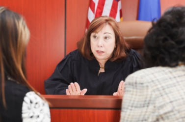 A judge discusses a case with two attorneys. A judge discusses a case with two attorneys.