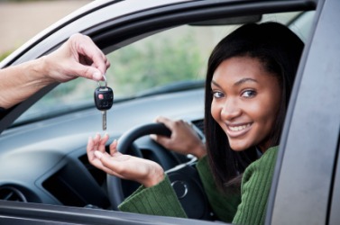 A woman receives the key to the car. A woman receives the key to the car.