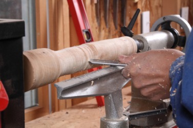 A man using a lathe on a piece of wood. A man using a lathe on a piece of wood.