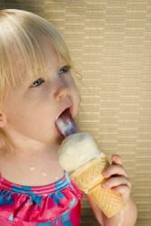 A little girl licks an ice cream cone. A little girl licks an ice cream cone.
