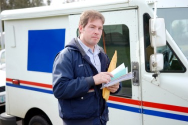 A mail carrier in front of his truck. A mail carrier in front of his truck.