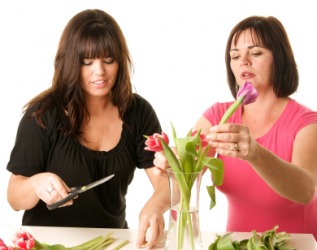 Two women manipulate flowers to form a pleasing arrangment. Two women manipulate flowers to form a pleasing arrangment.