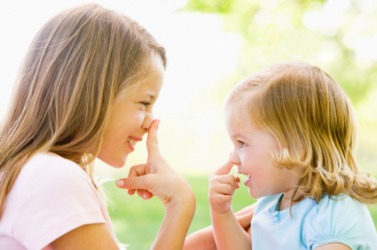 A little girl mimics her big sister. A little girl mimics her big sister.