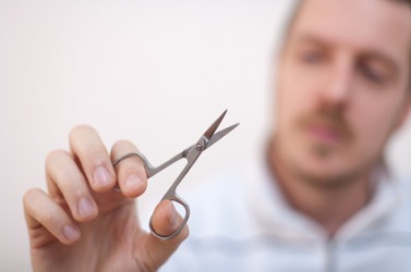 A man holding a pair of nail scissors. A man holding a pair of nail scissors.