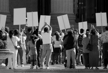 A group of people hold up protest signs. A group of people hold up protest signs.
